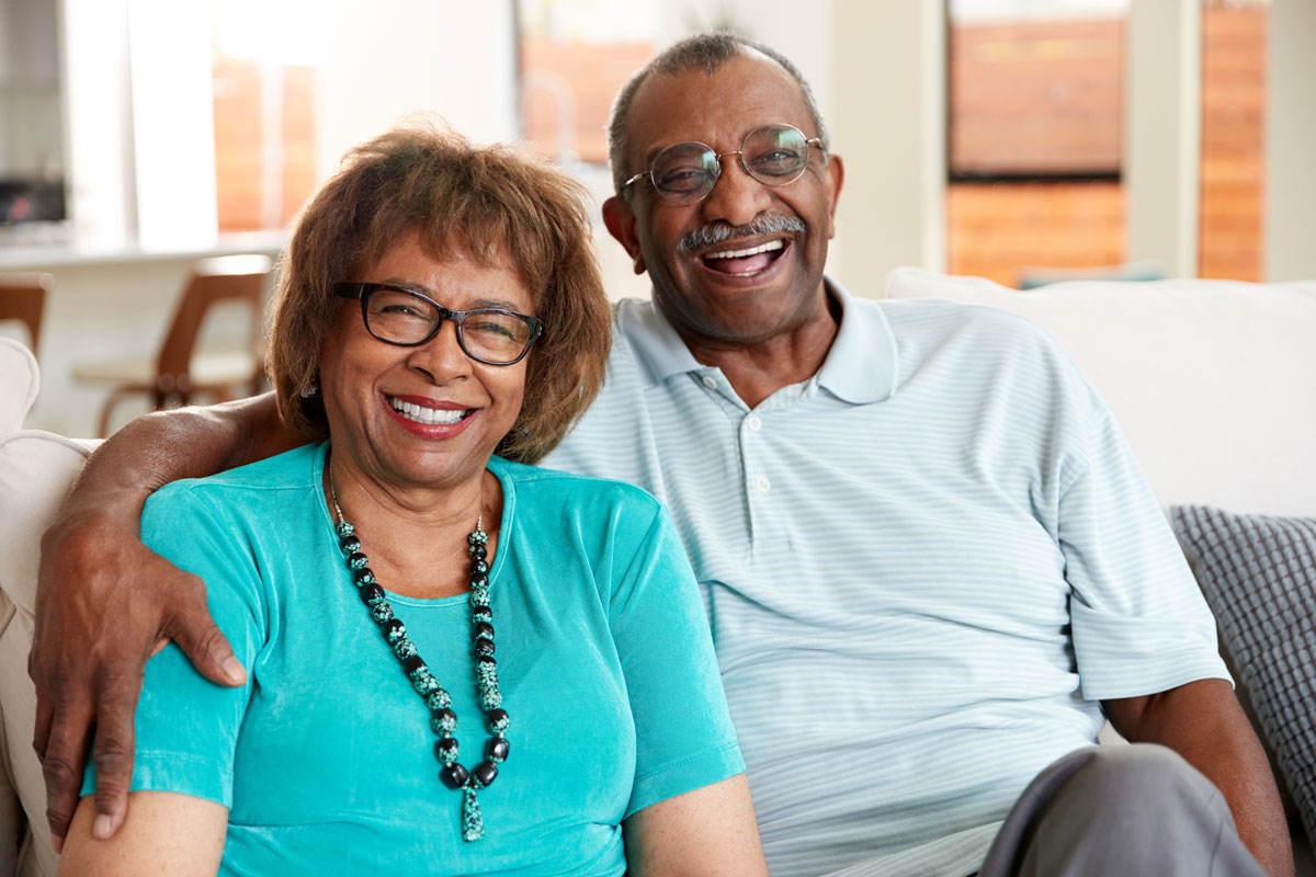 senior couple sitting on couch smiling