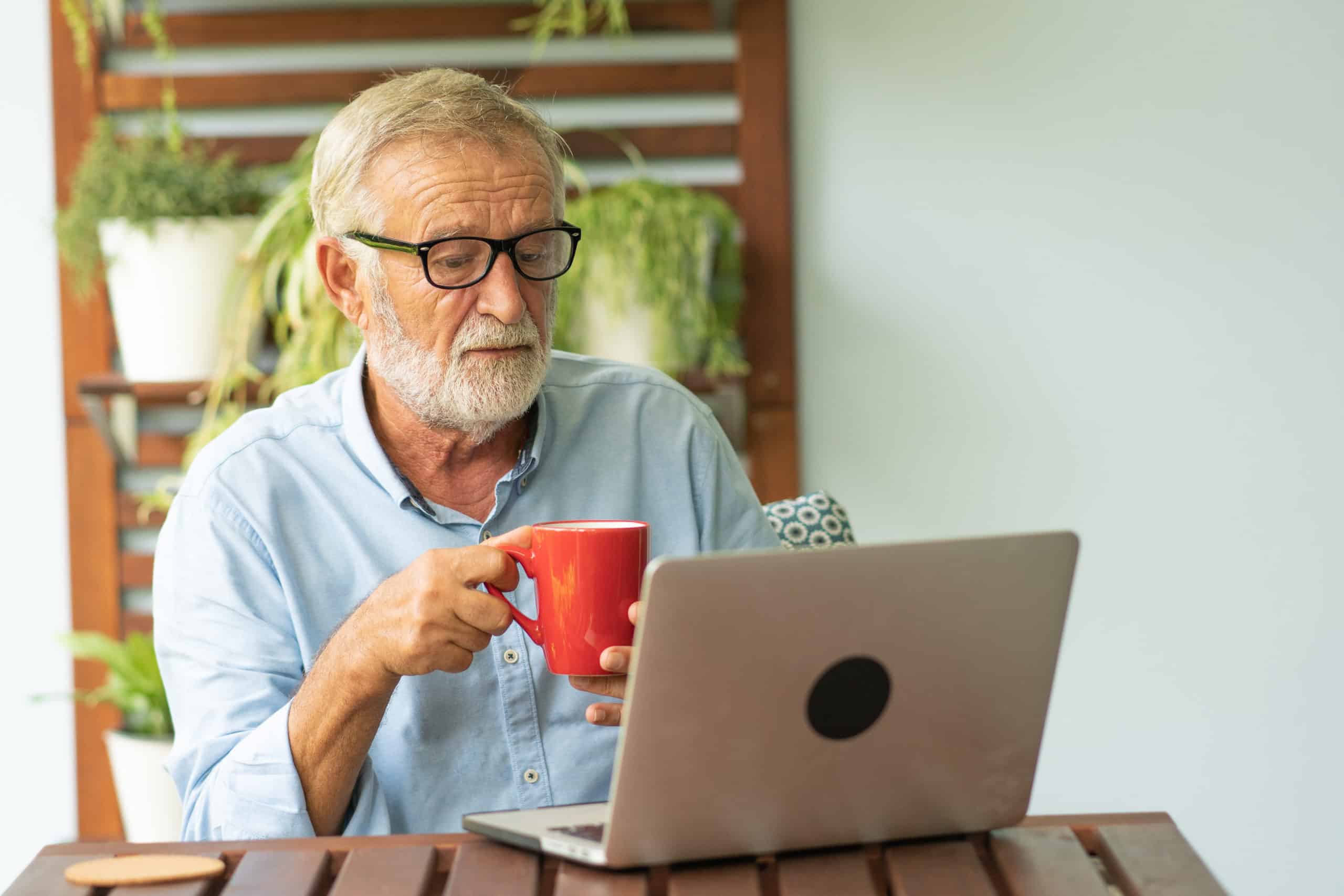 senior man drinking coffee on laptop