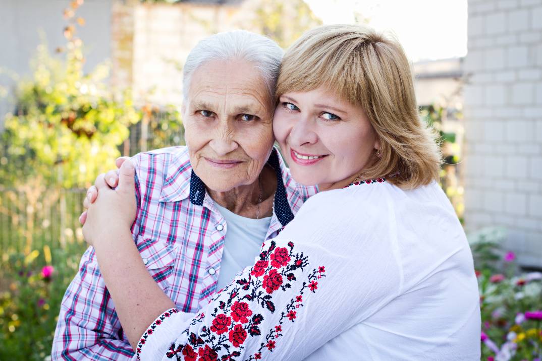 Daughter caregiver hugging senior mom