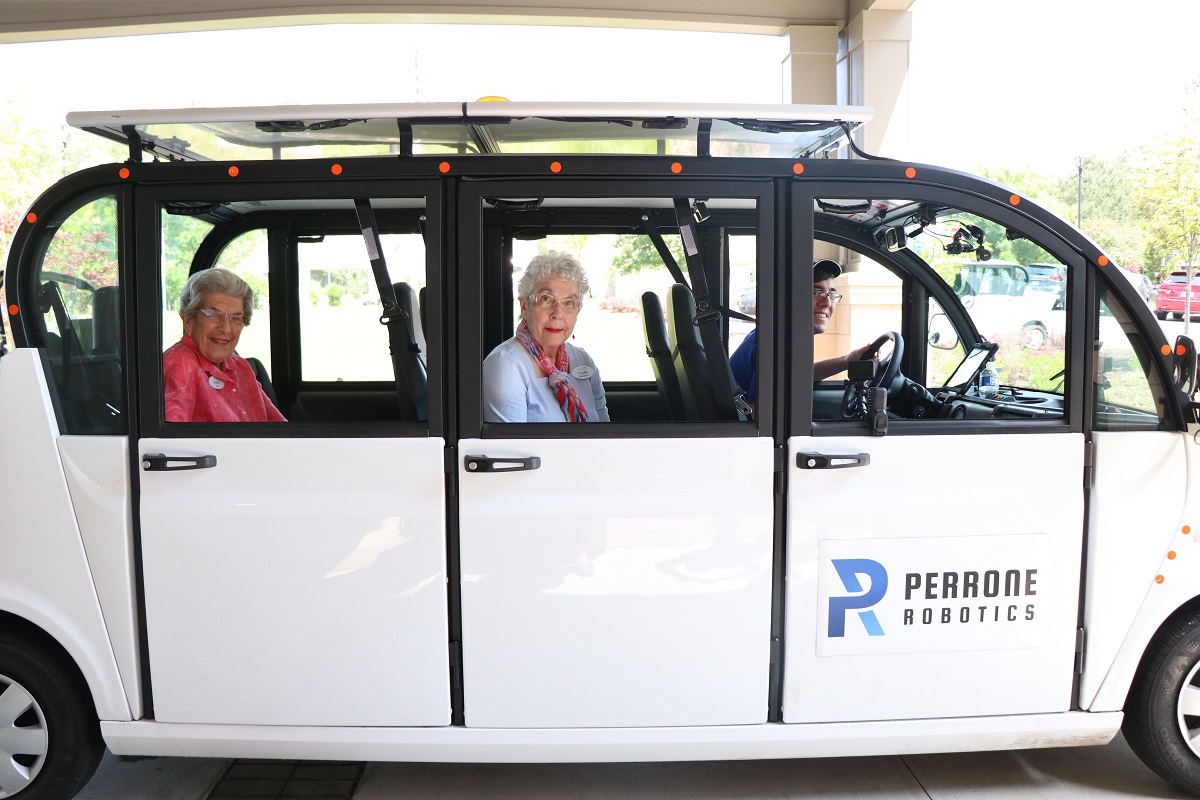 Senior women and male driver posing for picture in self-driving car