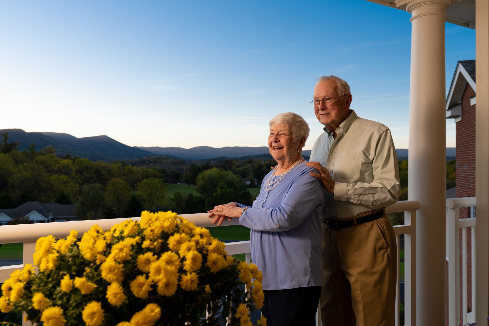 Senior couple standing outside the back porch looking at mountains