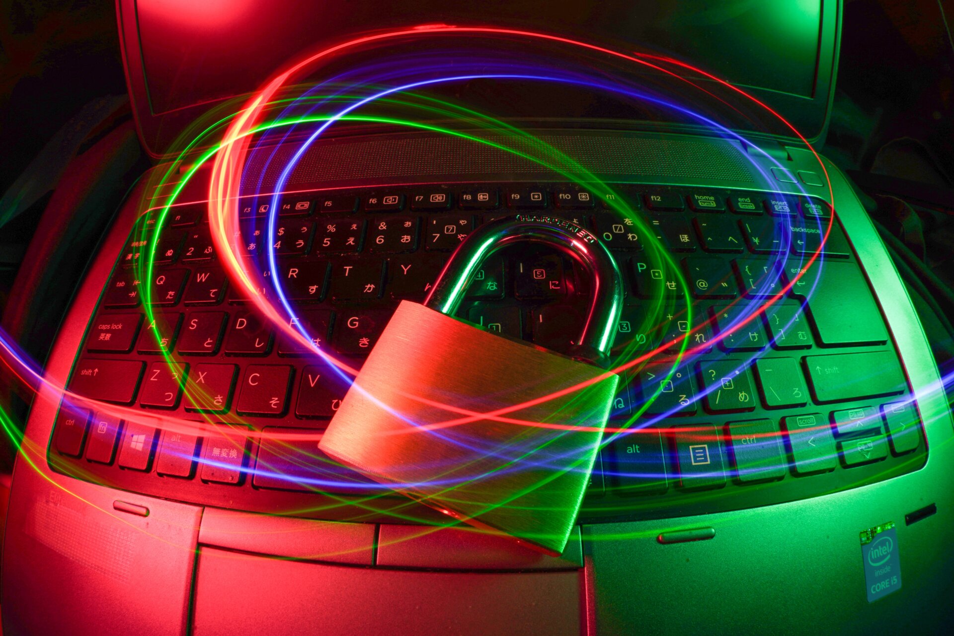 A giant key lock on a laptop with neon swirls above it implying cybersecurity