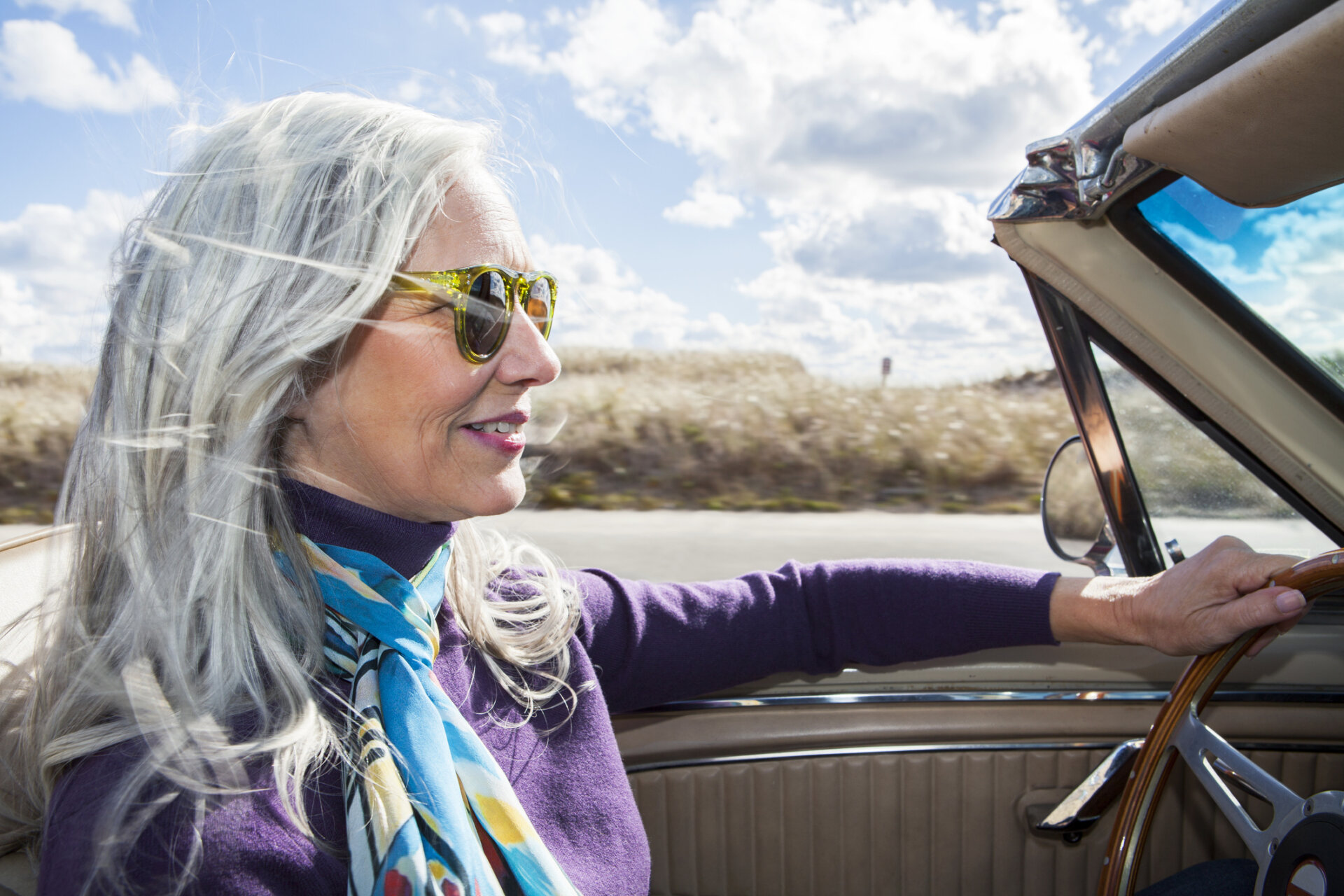 Woman in a car with her hair blowing in the wind.