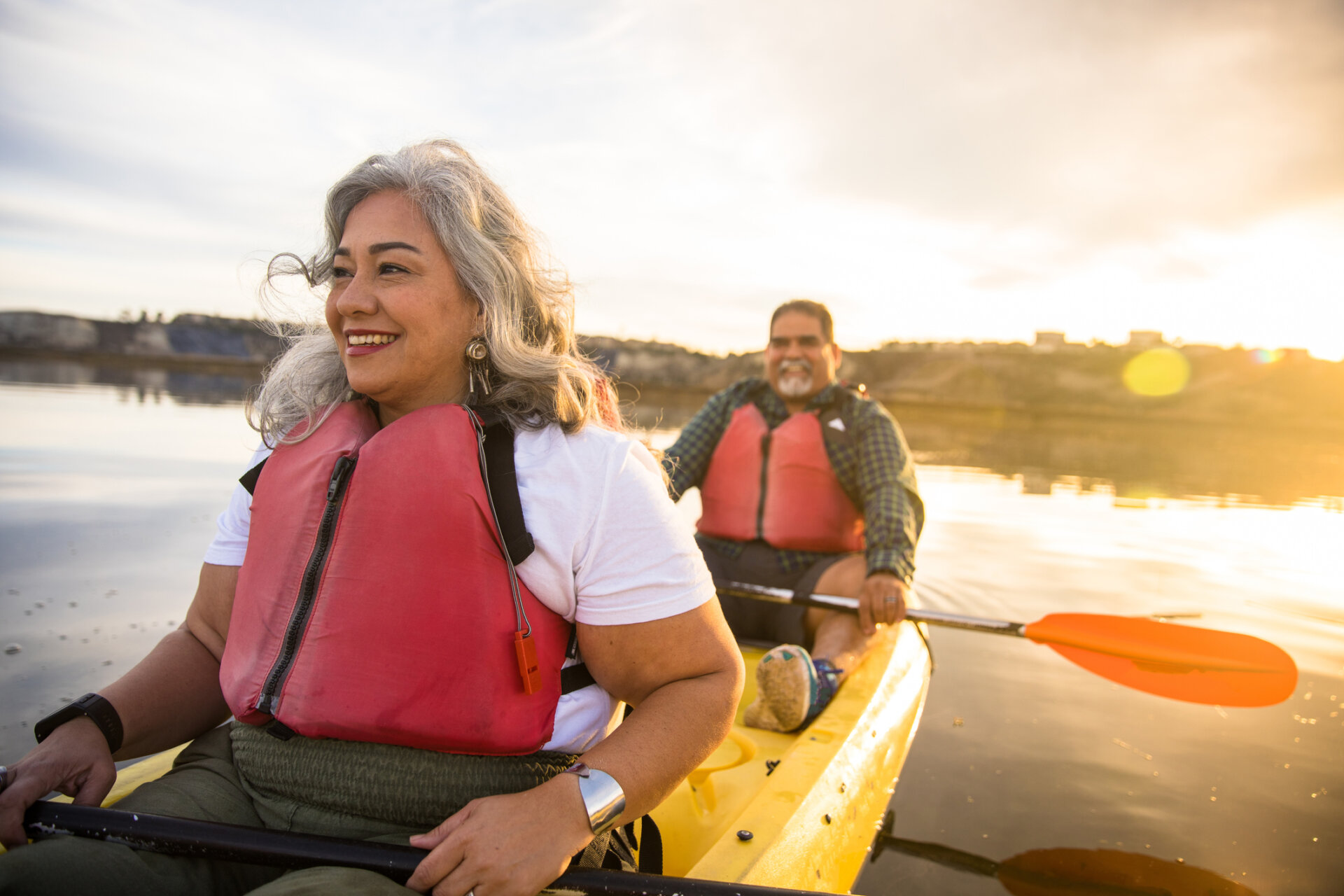 a senior woman and a senior man are padding on a river