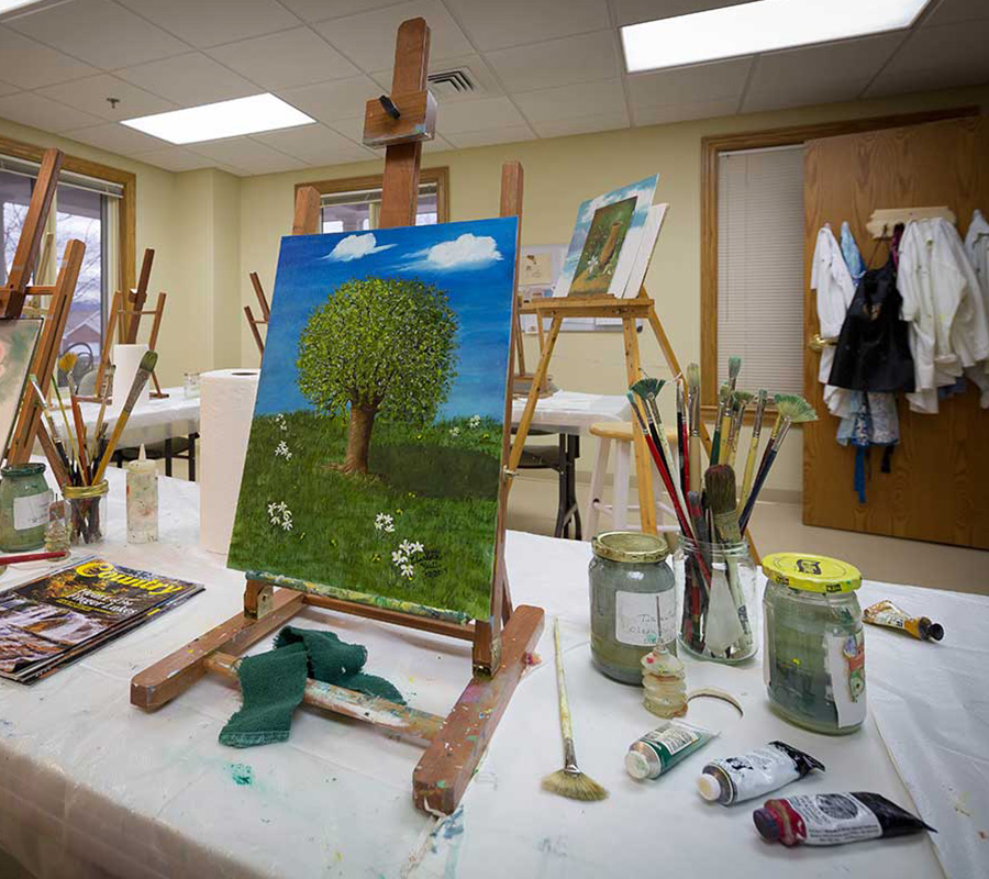 Art studio with easels and painting supplies in a creative community space.