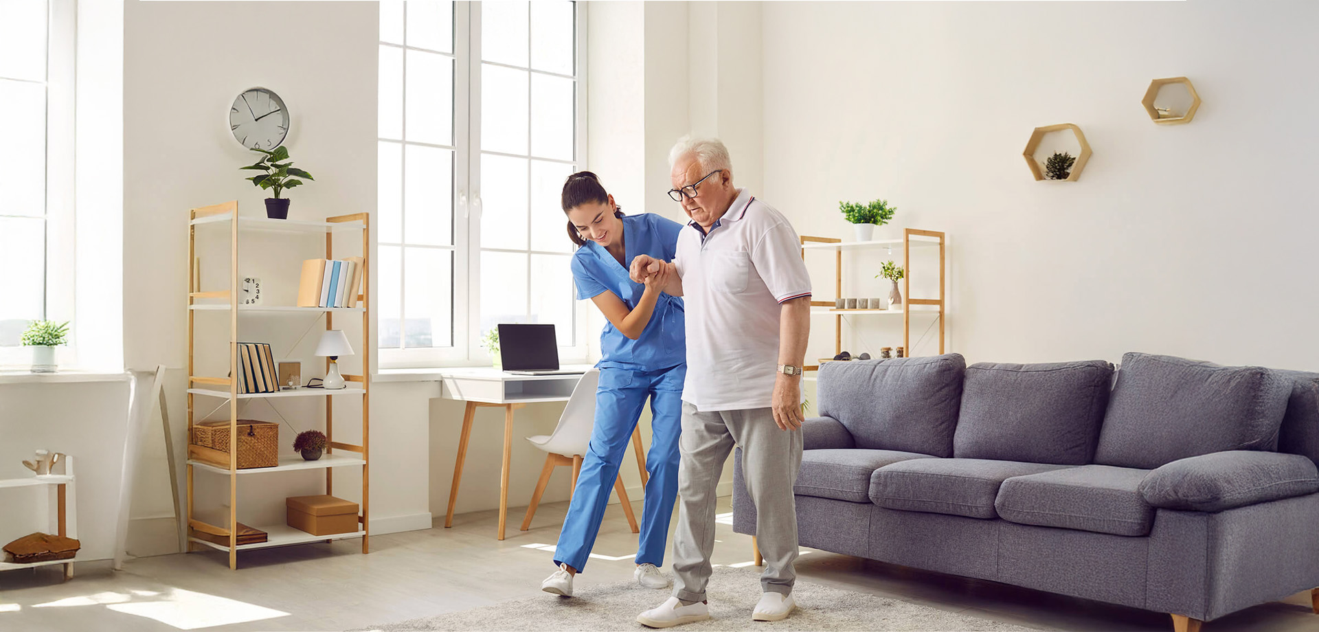 Nurse assisting elderly man to walk in a cozy living unit with modern decor.