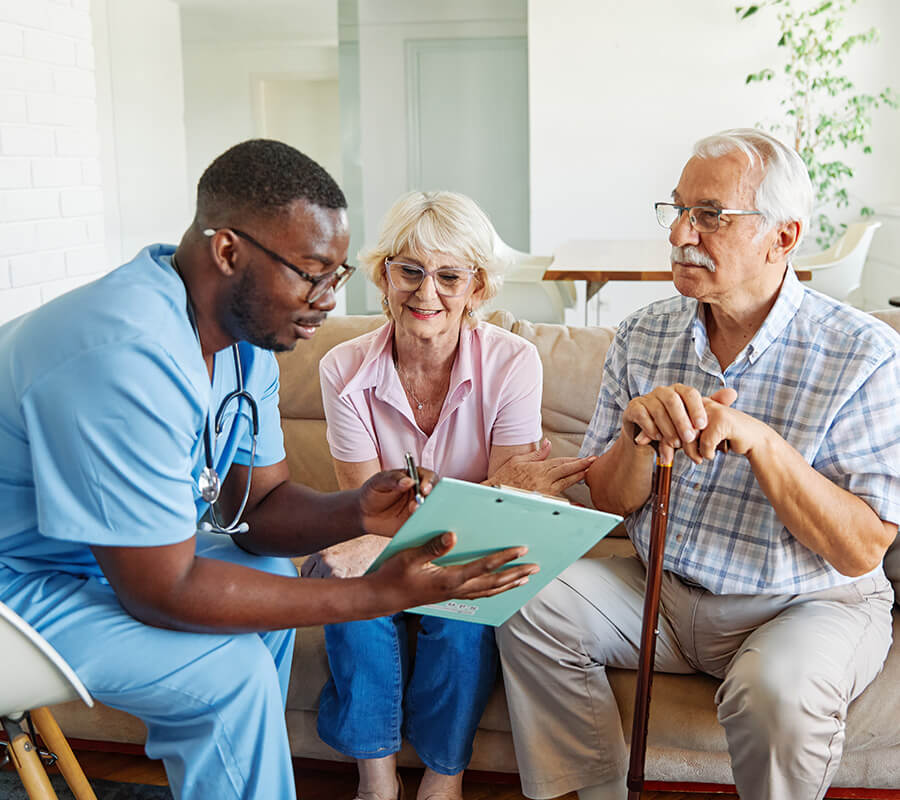 Healthcare professional discussing care plan with senior couple in a living unit.