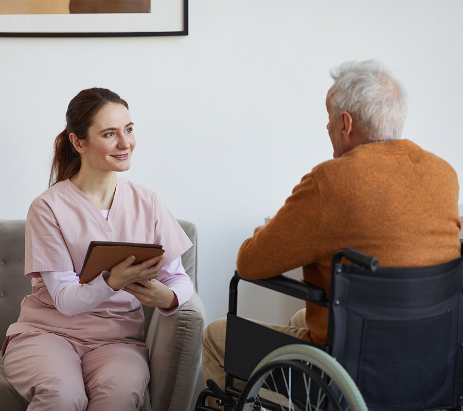 Caregiver talks with a senior in a wheelchair inside a living unit.