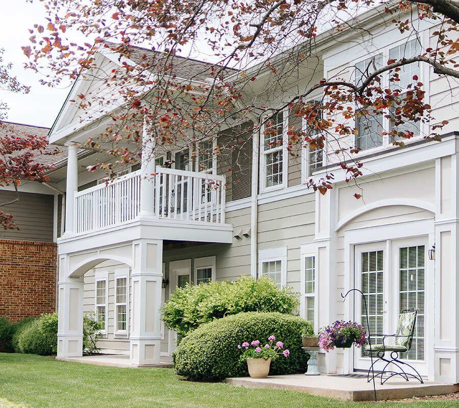 Elegant senior living units with white balconies and lush garden landscape.