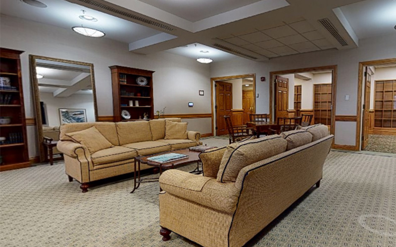 Cozy communal living area with sofas and bookshelves in a senior living facility.