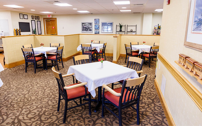 Dining area with tables and chairs in a senior living community.