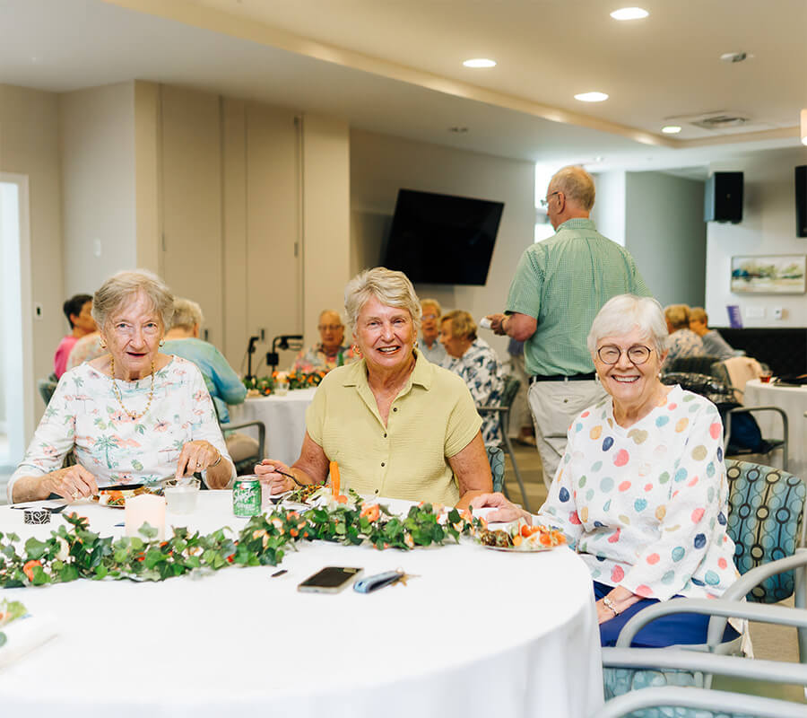Seniors enjoying a meal together in a bright dining room of a community unit.