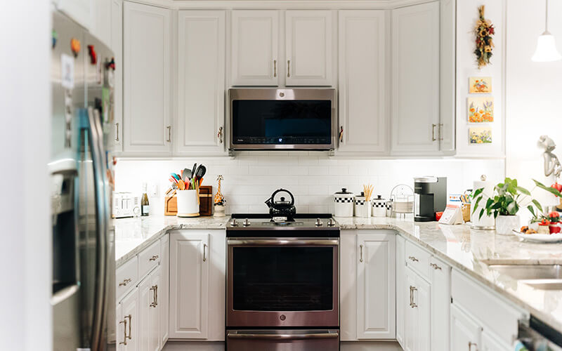 Contemporary Unit Kitchen Modern kitchen with white cabinets, stainless steel appliances, and marble countertops.