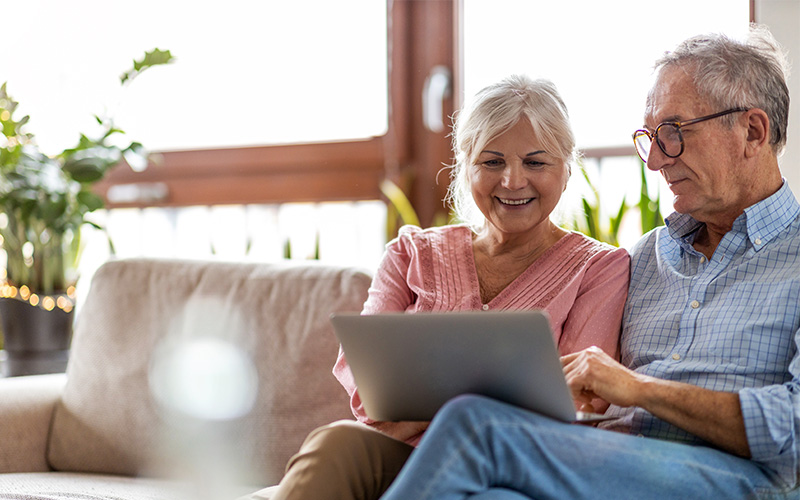 Older couple enjoying time together using a laptop in a cozy living space.
