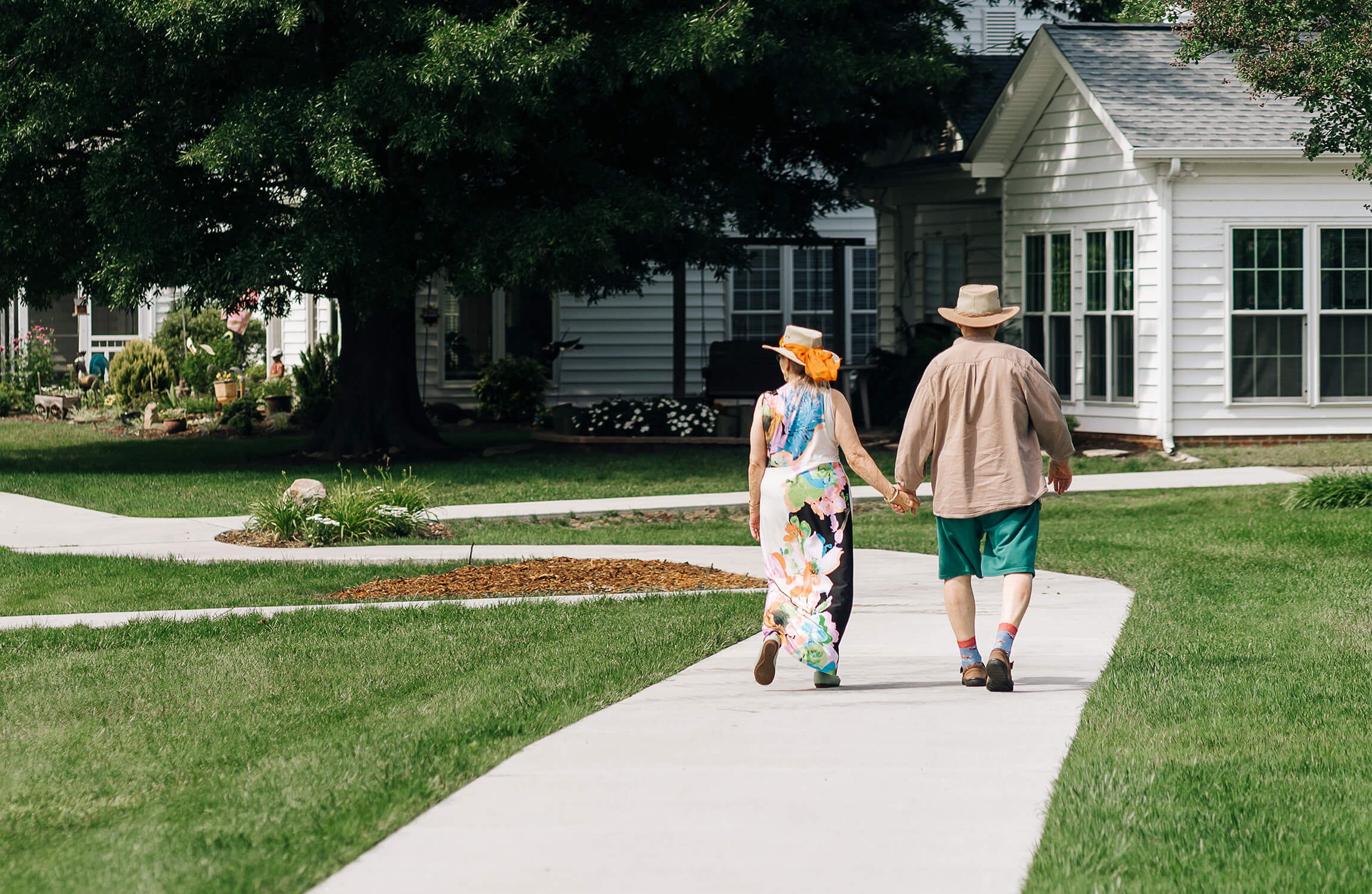 Couple Enjoying a Walk in the Community Garden Elderly couple walking hand in hand in a lush garden of a community with white units.