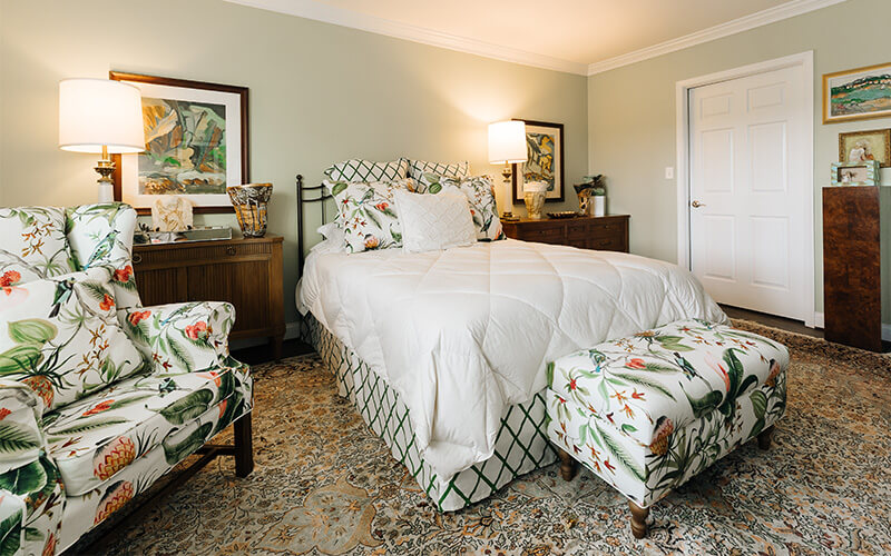 Warm and Inviting Bedroom Design Cozy bedroom in a senior living unit with floral armchair, bed, and decor.