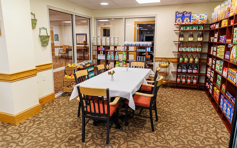 Cozy dining area in a senior living unit with well-stocked shelves and a table for six.