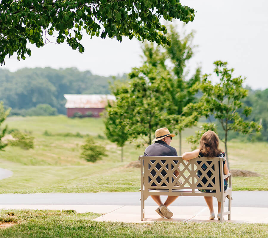Two adults sitting on bench enjoying the view at Culpeper senior living