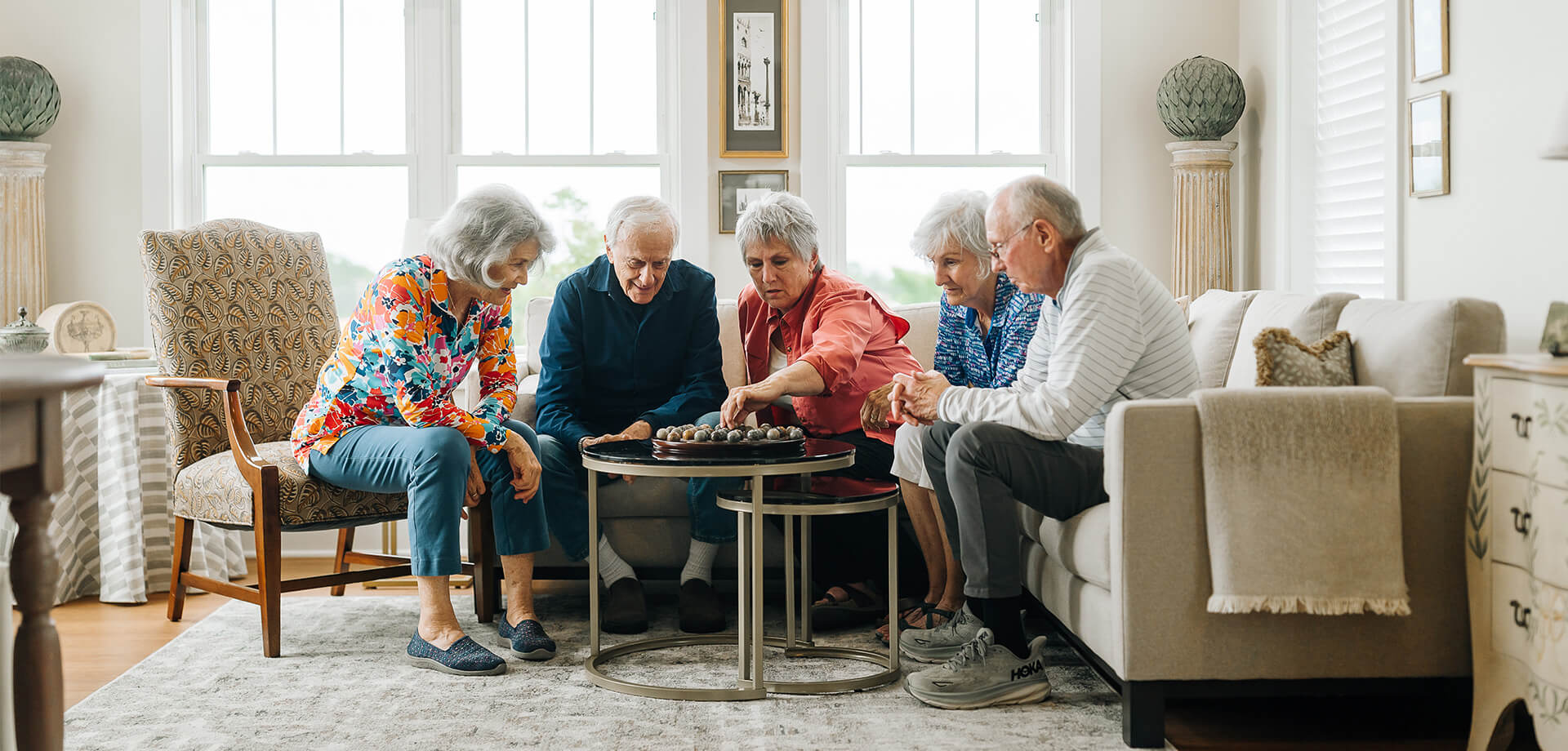 Senior friends play a board game in living room