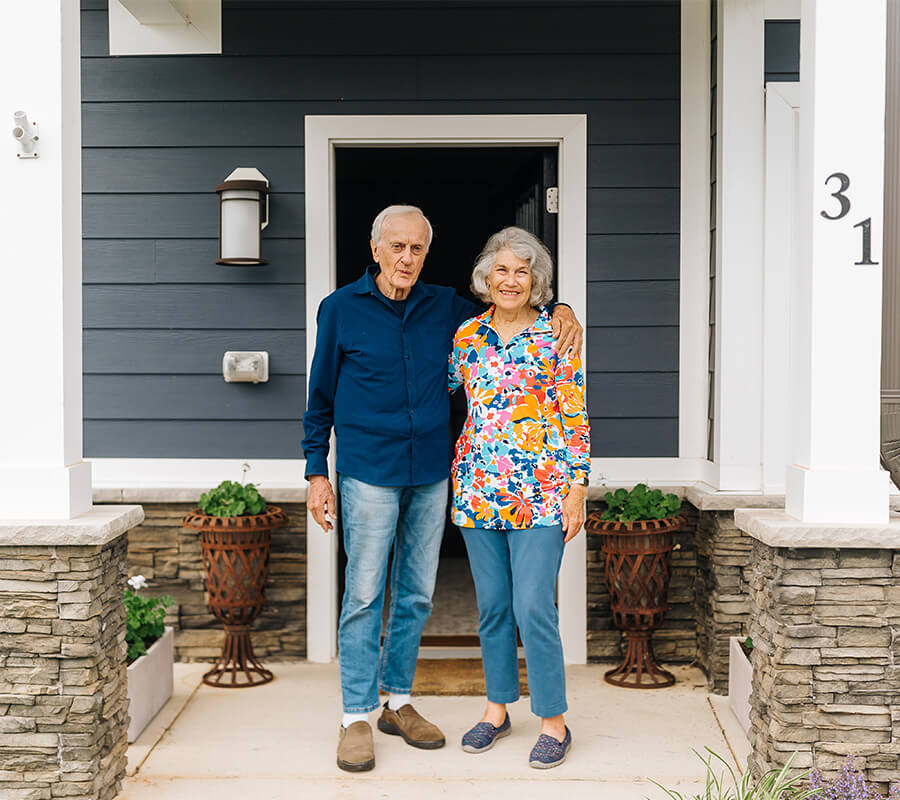 Senior couple smile on their senior independent living home's doorstep