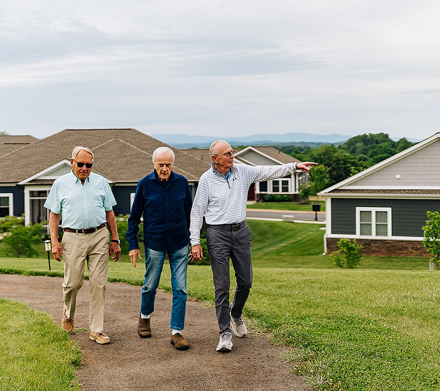 Senior friends walk on path through neighborhood