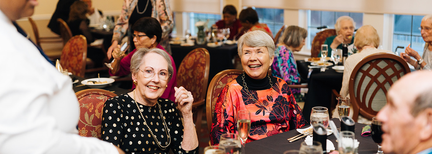 Residents enjoying a meal and conversation in a community dining area.