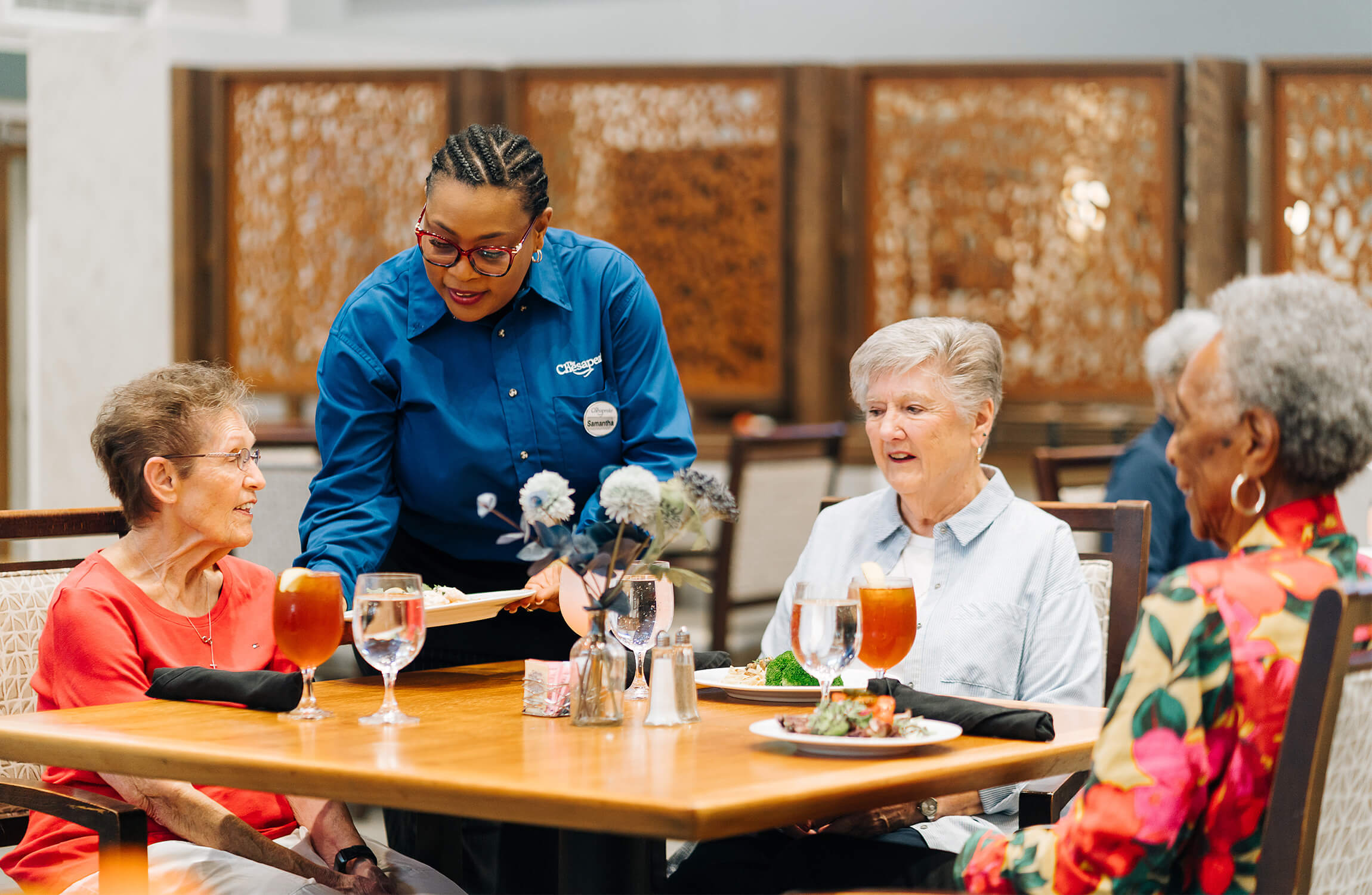 Dining Service for Residents Dining staff serving meal to residents in a communal dining room.