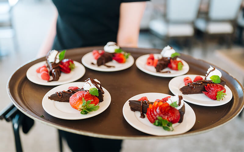 Tray of chocolate desserts with strawberries in dining area of a senior living unit.