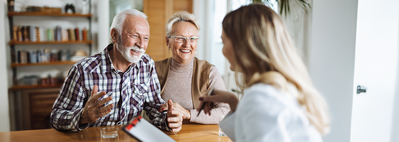Smiling elderly couple meeting with a consultant in a cozy living space.