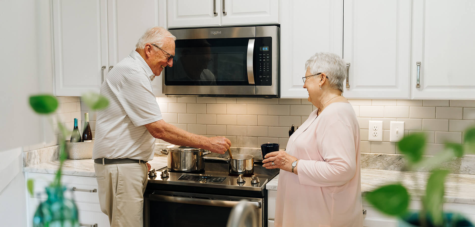 Elderly couple cooking together in a modern kitchen, sharing a joyful moment.