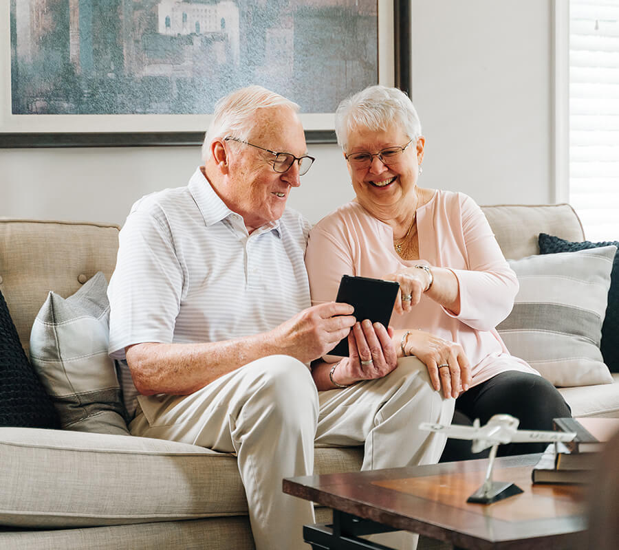 Elderly couple sharing a happy moment on a sofa in a cozy unit living room.