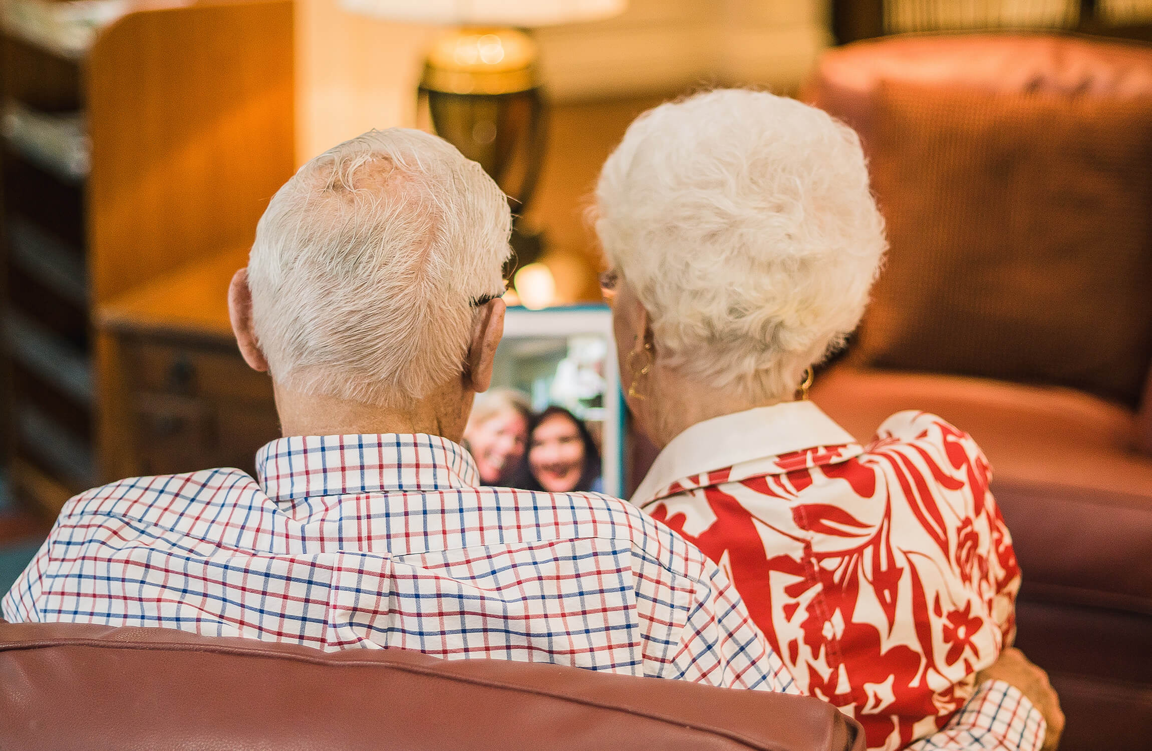 Elderly couple in unit on a video call with family on a tablet.