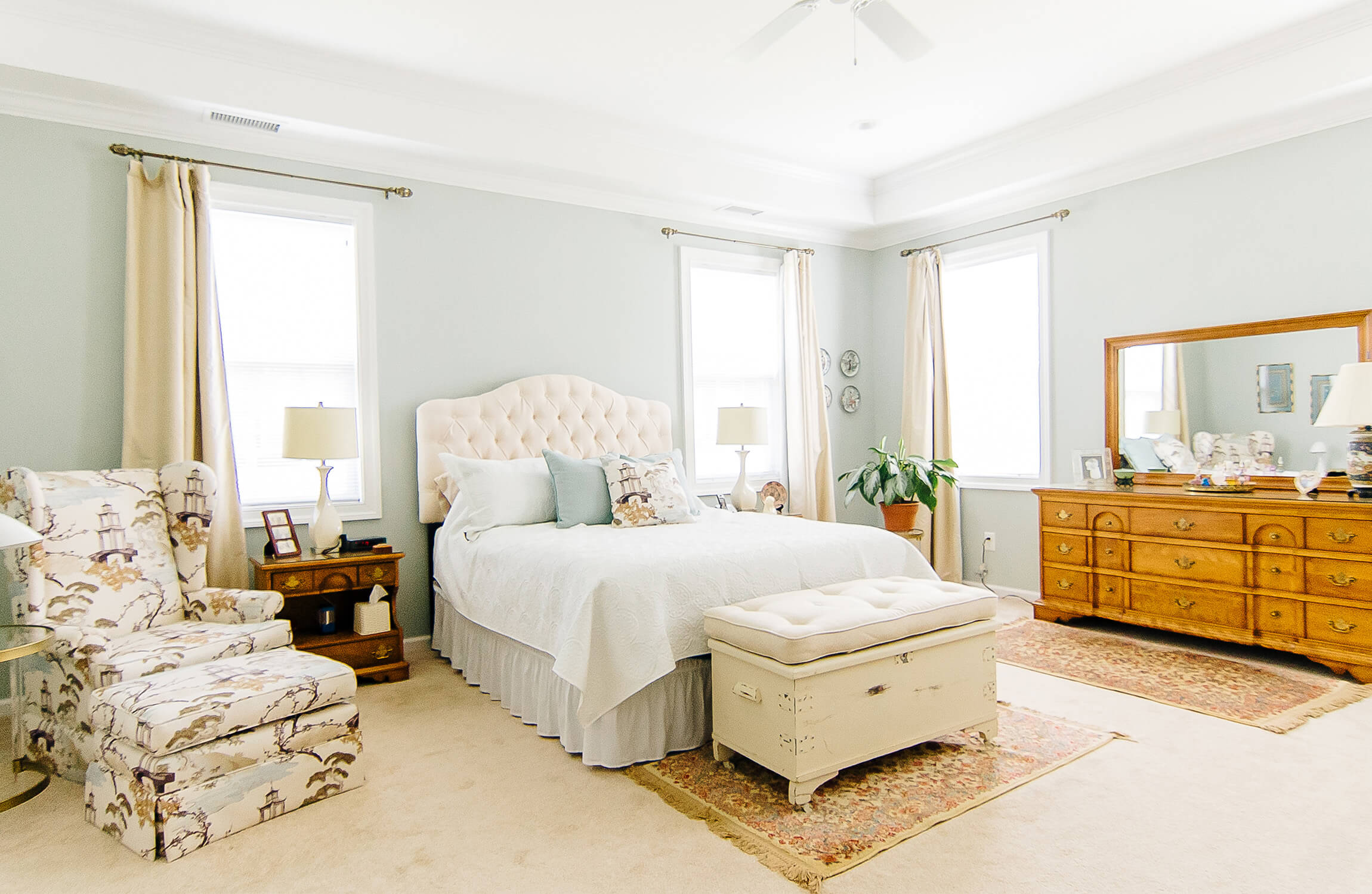 Spacious bedroom with a tufted bed, armchair, and dresser in a senior living unit.