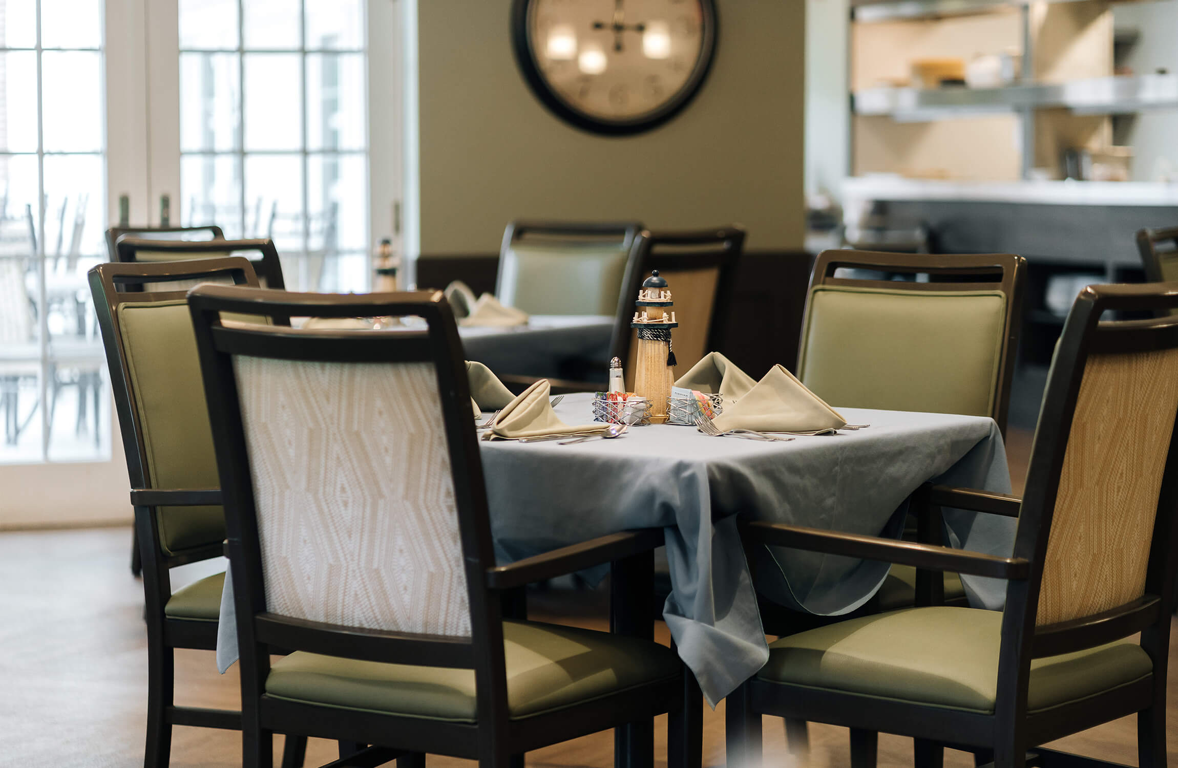 Elegant dining area with green chairs and a neatly set table in a senior living unit.