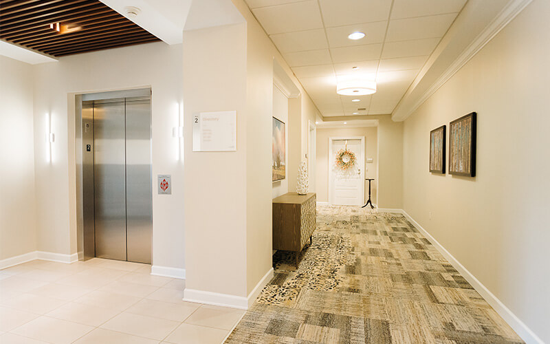 Elevator and Hallway in Senior Living Community Bright hallway with elevator and decorated door in senior living community.