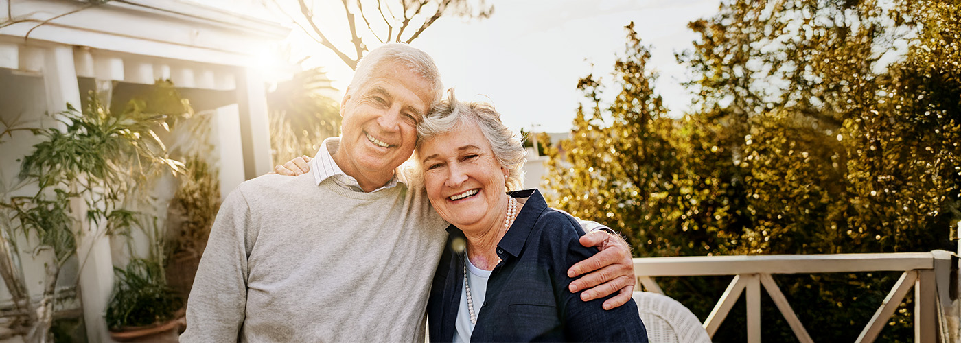 Smiling senior couple embracing outdoors at a housing community.