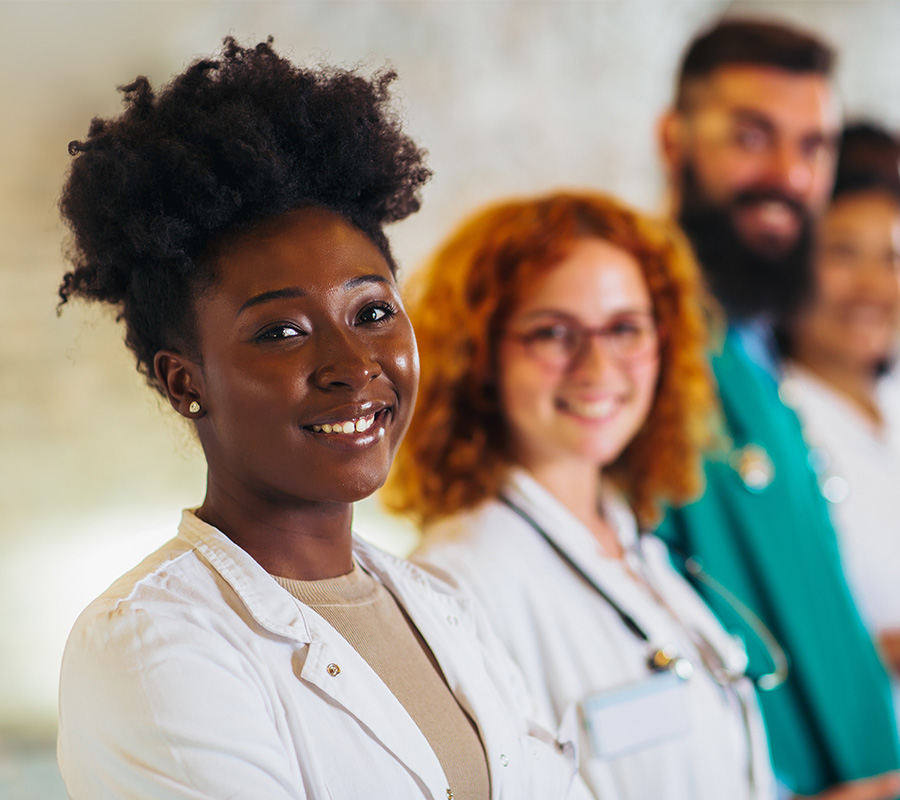 Smiling healthcare professionals in a row inside community building.