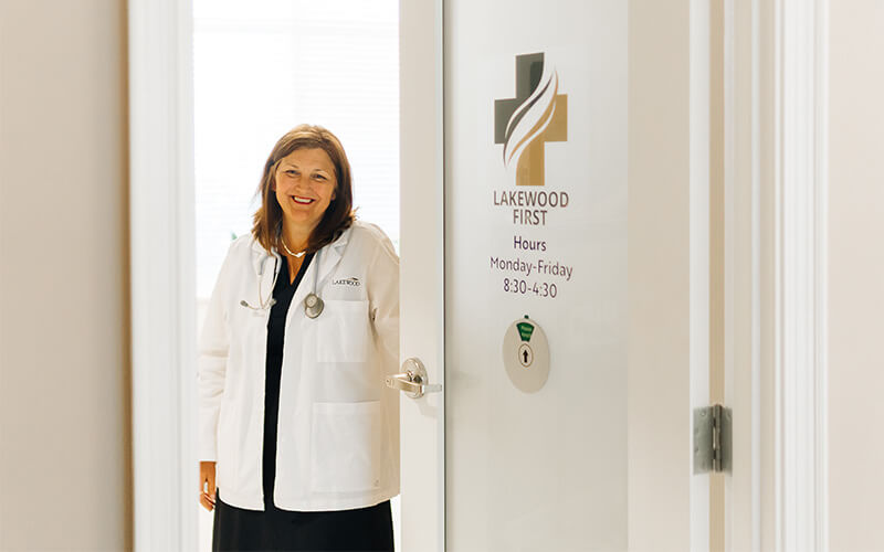 Doctor in white coat stands at entrance of healthcare unit in a senior community.