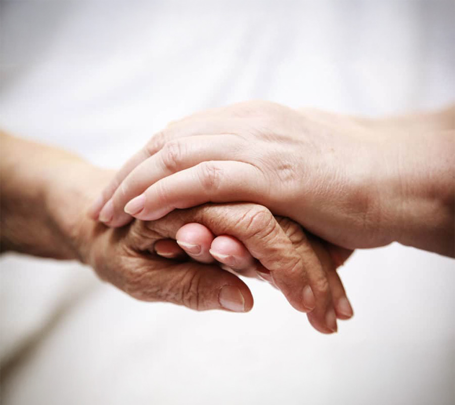 Elderly and younger hands clasped gently in a caring gesture.