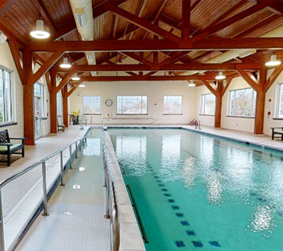 Indoor pool with wooden beams and large windows in a community center.