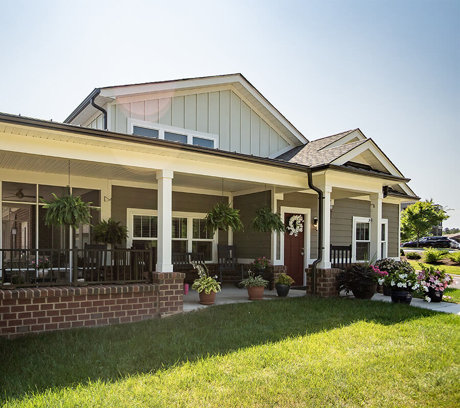 Charming single-story building with porch and plants at a senior living community.