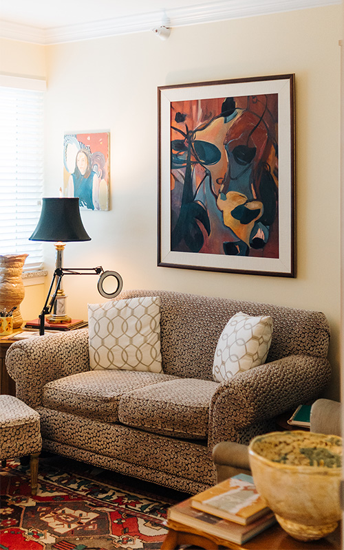 Cozy living room with plush sofa, abstract art, and a warm floor lamp.