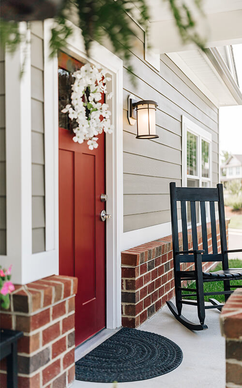 Inviting Unit Porch with Red Door and Rocking Chair Front porch of a unit with a red door, rocking chair, and floral wreath.