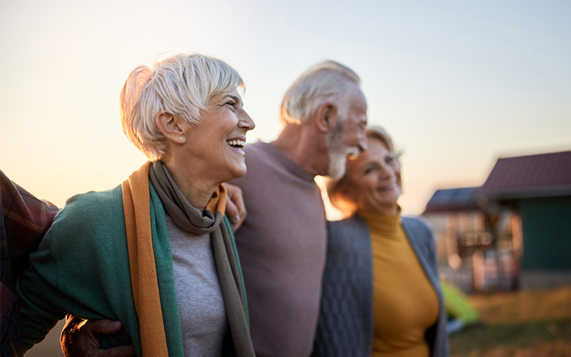 Senior friends walk in park during sunset