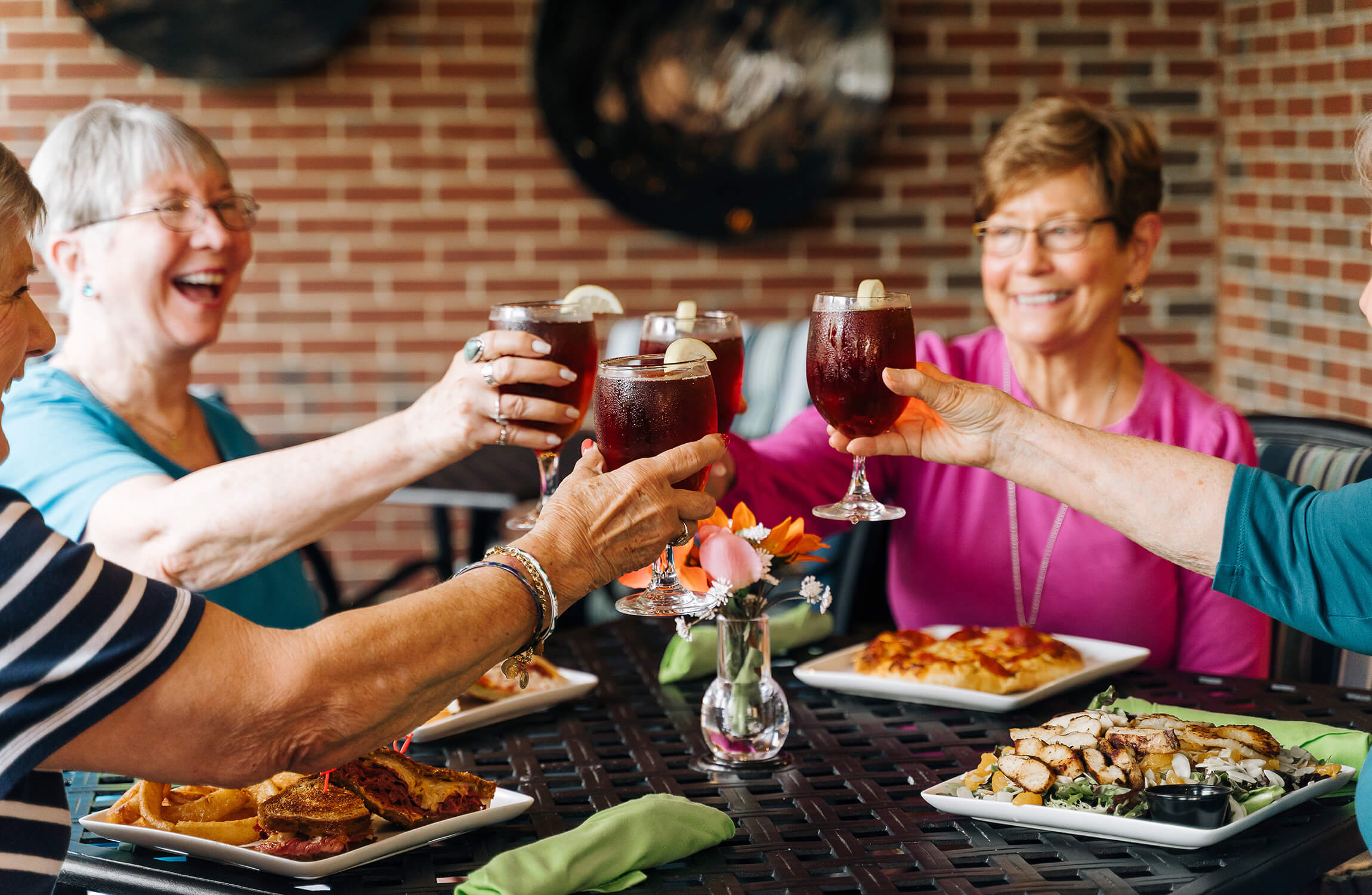 Group of seniors clinking glasses and enjoying lunch at a community dining area.