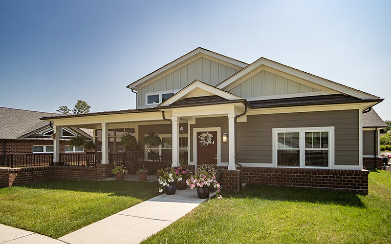 Front view of a modern unit with a porch and flower pots in a senior living community.