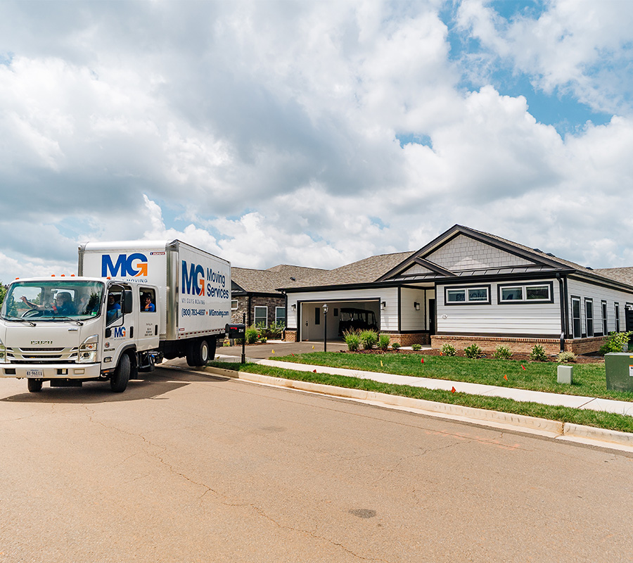 Moving truck parked in front of a newly built senior living community with individual units.