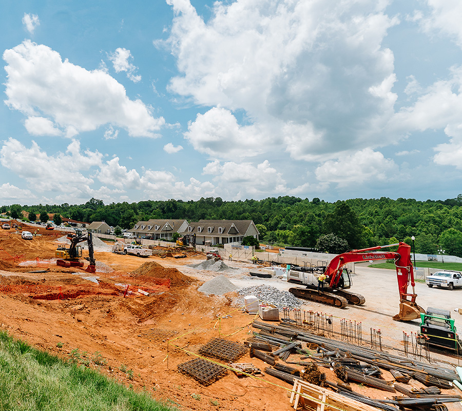 Construction site for new senior living units with machinery under a partly cloudy sky.