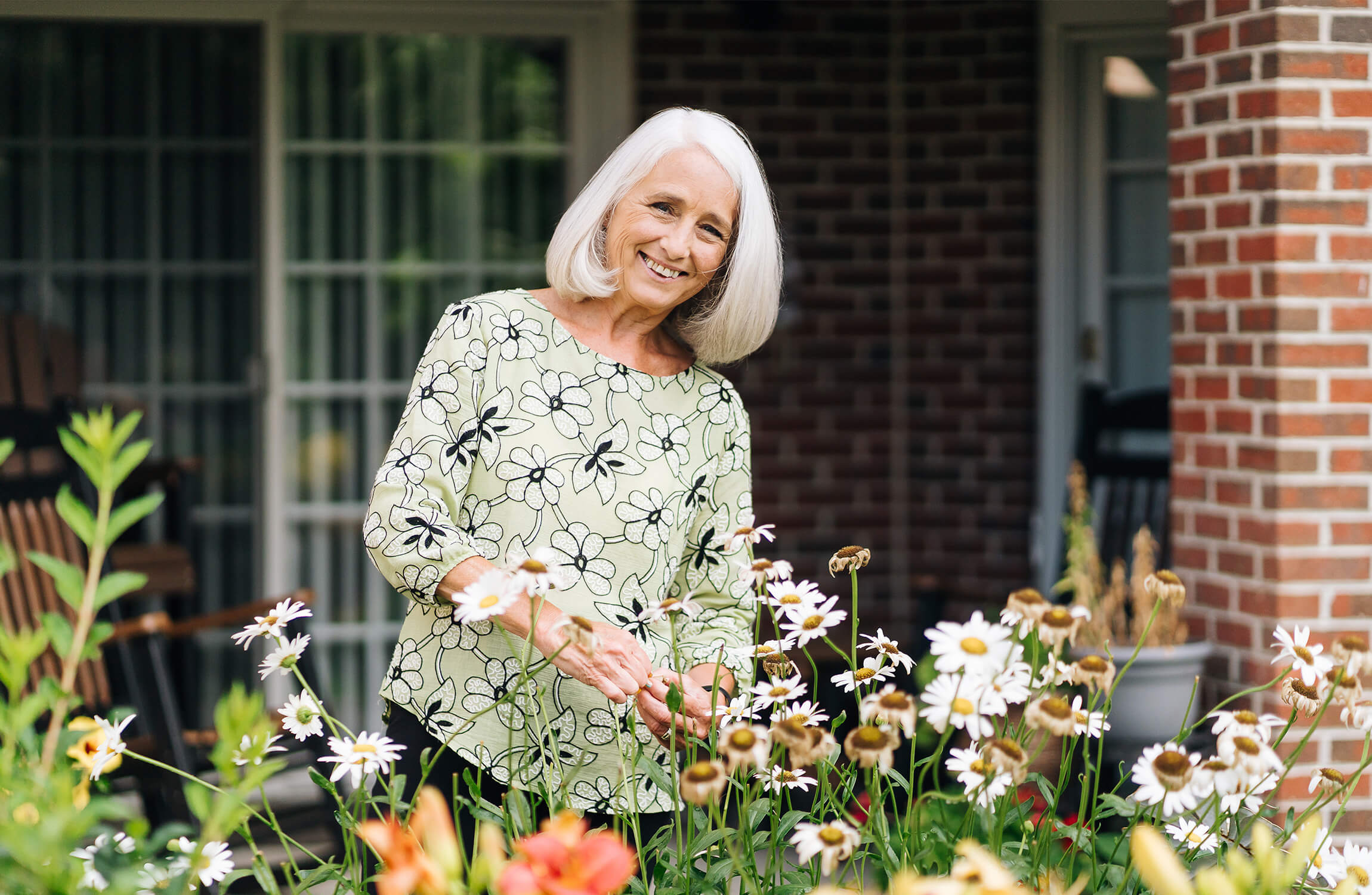 Resident Enjoying Gardening Smiling woman tending garden in senior living community.