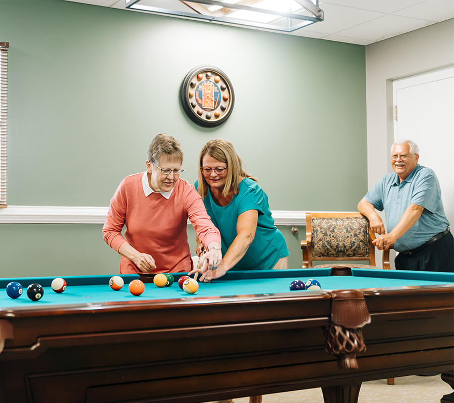 Residents engaging in a friendly game of pool in a vibrant community common room.